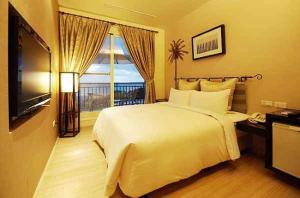 una camera da letto con un grande letto bianco e una televisione di Golden Bay Holiday Inn a Kenting