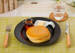 a black plate with pancakes and butter on a table at HOTEL&SPA SIESTA ( Adult Only) in Shijonawate