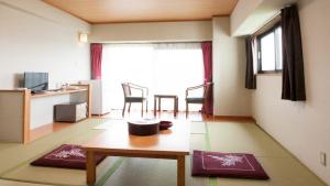 ein Wohnzimmer mit einem Tisch und ein Zimmer mit einem Fenster in der Unterkunft Hotel New Koyo in Kusatsu