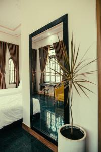 - une chambre avec un miroir et une plante en pot dans l'établissement HOUSE OF LÝ, à Hue