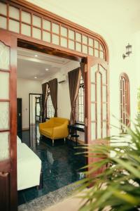 a living room with a yellow couch and a table at HOUSE OF LÝ in Hue