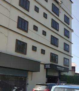 a large building with cars parked in front of it at HISHAM SUITES in Ernakulam