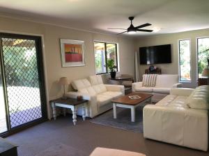 a living room with white furniture and a sliding glass door at Bowral Bungalow in Bowral