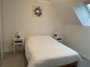 un letto bianco in una stanza con due tavoli di la petite loge ad Ay