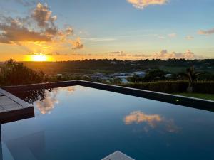 une piscine avec vue sur le coucher du soleil en arrière-plan dans l'établissement Villa Sinoé, à Petit-Bourg