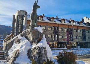 a statue of a giraffe on a rock in front of a building at SOMMOS Hotel Aneto in Benasque