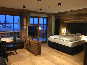 - une chambre avec un grand lit et une télévision dans l'établissement Appartements Innerkofler Mountain Home, à San Candido