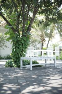 a white bench sitting in front of a tree at Sevilla Resort Magelang in Magelang