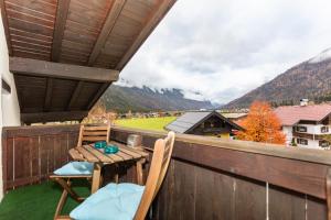 a wooden table and chairs on a balcony with mountains at Ferienwohnung Steinplatte in Waidring