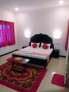 a bedroom with a bed with red pillows and a table at Amritchandra homestay and hostel in Udaipur