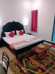 a bedroom with a bed with red pillows and a table at Amritchandra homestay and hostel in Udaipur