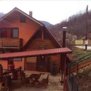 eine Blockhütte mit einem Picknicktisch davor in der Unterkunft Planinska IDILA in Crni Vrh