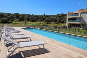 a row of lounge chairs next to a swimming pool at CALADEA Locations de Vacances 5 étoiles, piscine chauffée in Porto-Vecchio