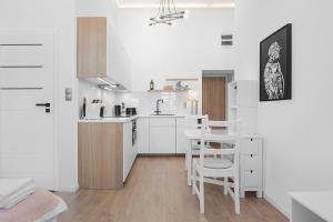 cocina con armarios blancos, mesa y sillas en Princess Dream apartment in the heart of Wroclaw, en Wroclaw