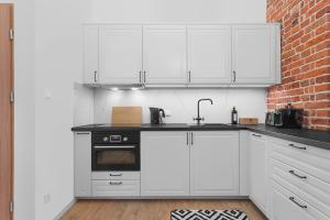 a kitchen with white cabinets and a brick wall at Grey Panther Apartment in the Heart of Wroclaw in Wrocław