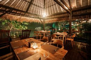 a restaurant with tables and chairs and a roof at One Degree Sunset Hill Leisure in Uluwatu