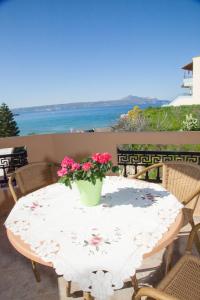 een tafel met een vaas met bloemen op een balkon bij Meandros in Almirida