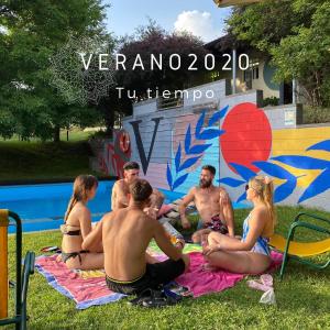 a group of people sitting on a blanket by a pool at Camping Alta Ribagorça in El Pont de Suert