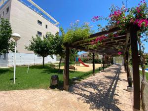 a wooden pergola in a park with a playground at Apartamento Aguamar in Denia