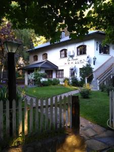 uma casa branca com uma cerca à frente. em Posada de la Flor em San Carlos de Bariloche