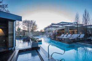 a swimming pool with chairs and a building at Fletcher Wellness-Hotel Kamperduinen in Kamperland