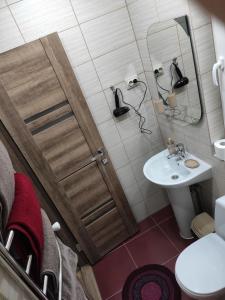 La salle de bains est pourvue d'un lavabo et d'une porte avec un miroir. dans l'établissement Сімейний відпочинок, à Trouskavets