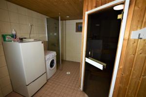 a small kitchen with a refrigerator and a washing machine at Pyhtään Vuokramökit in Tuuski