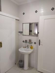 Guarujá Enseada - Apto 200m da praia - 02 dorm. Wi-fi + AR + Estacionamento في غوارويا: حمام أبيض مع حوض ومرآة +14 صورة