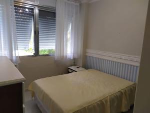 Guarujá Enseada - Apto 200m da praia - 02 dorm. Wi-fi + AR + Estacionamento في غوارويا: غرفة نوم صغيرة بها سرير ونافذة