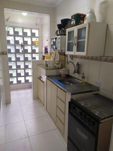 Guarujá Enseada - Apto 200m da praia - 02 dorm. Wi-fi + AR + Estacionamento في غوارويا: مطبخ بدولاب بيضاء وموقد اسود