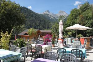 a patio with tables and chairs with mountains in the background at La Cordée in Ovronnaz