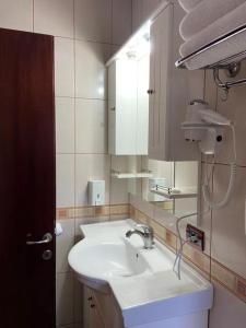 a bathroom with a white sink and a mirror at Hotel George in Korçë