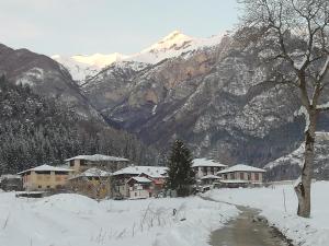 een dorp bedekt met sneeuw met een berg op de achtergrond bij Appartamento Cillà in Comano Terme