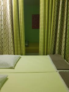 1 dormitorio con 1 cama con cortinas amarillas y espejo en La Case Bonheur, en Sainte-Anne