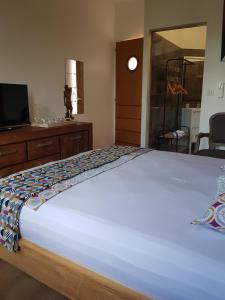 1 dormitorio con 1 cama blanca grande y TV en La Case Bonheur, en Sainte-Anne