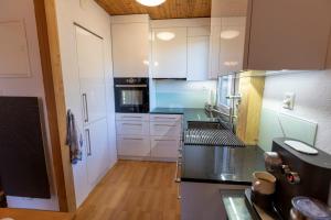 una cocina con armarios blancos y electrodomésticos negros en Les Crosets Apartment Miroi 23, Val d'Illiez en Les Crosets