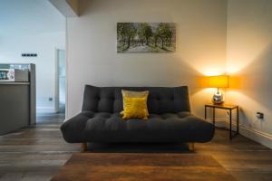 a couch in a living room with a yellow pillow at Private, Detached Annex with On-Street Parking in Cardiff