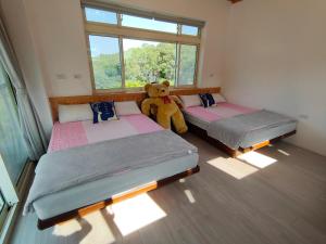 una habitación con 2 camas con un osito de peluche sentado entre ellas en Fei Ying Homestay en Tongxiao