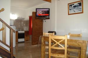 a living room with a table and a television on a wall at Cabañas Aldea Serrana in Sierra de la Ventana