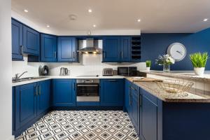 a blue kitchen with white appliances and blue cabinets at Plymouth Central Duplex Apartment - Private Parking - Sleeps 6 - Habita Property in Plymouth