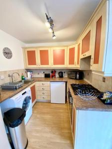 uma cozinha com armários laranja e uma máquina de lavar louça branca em Wellingtonia Court Apartment em Inverness