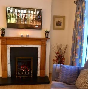 a living room with a fireplace with a television above it at Wellingtonia Court Apartment in Inverness