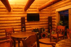 ein Wohnzimmer mit Tischen und einem TV in einer Blockhütte in der Unterkunft Miškiniškės in Ignalina