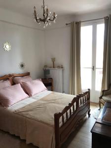 een slaapkamer met een bed met roze kussens en een kroonluchter bij Appartement climatisé F3 proche plage port et aéroport in Ajaccio