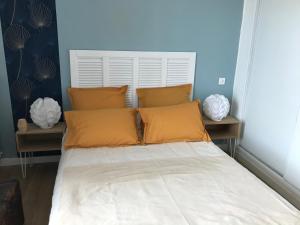 un letto con cuscini arancioni in una stanza di Appartement climatisé F3 proche plage port et aéroport ad Ajaccio