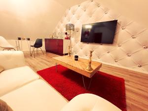 uma sala de estar com um sofá e uma televisão na parede em Redroom Loveroom Chambre Spa privative Insolite Thème 50 nuances de grey em Douchy-les-Mines