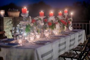 un lungo tavolo con candele e fiori in vasi di Villa Siena a Siena