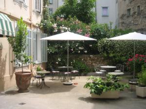 un patio al aire libre con mesas, sillas y sombrillas en Chanteclair en Cannes