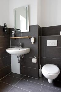 La salle de bains est pourvue d'un lavabo, de toilettes et d'un miroir. dans l'établissement Schickes Bielefeld Zentrum Appartement, à Bielefeld