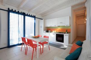 uma cozinha com uma mesa branca e cadeiras vermelhas num quarto em Casa Canoa - Le chiavi degli Iblei em Punta Braccetto